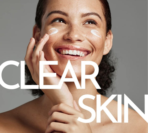 Female model smiling posed with cream on her cheeks.