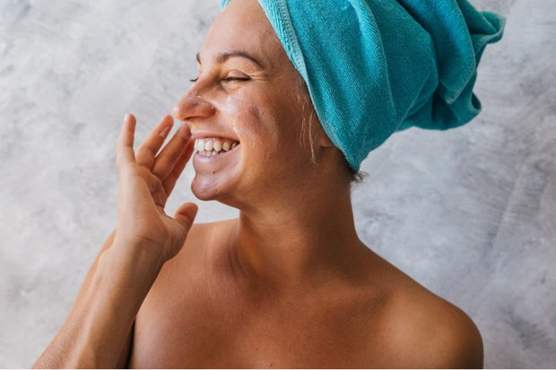 Female model smiling posed rubbing cream on her face